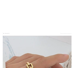 Close-up of gold chain link ring on finger with white marble texture background