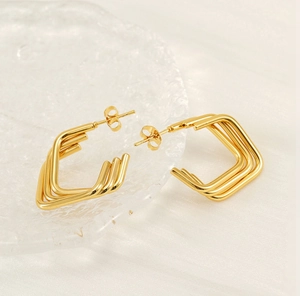 Gros plan détaillé des boucles d'oreilles géométriques triple couche en or sur soie