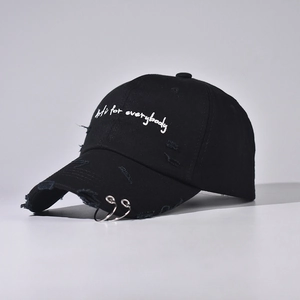 Detail of distressed black denim baseball cap with silver rings and white embroidery
