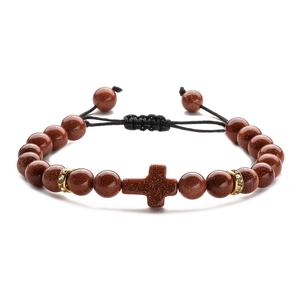 Macro detail of brown goldstone cross bracelet with sparkling beads and black braided cord