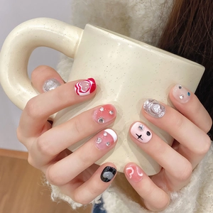 Handgefertigte Kunstnägel mit metallischen Herzen, bunten Strasssteinen und kunstvollem Design
