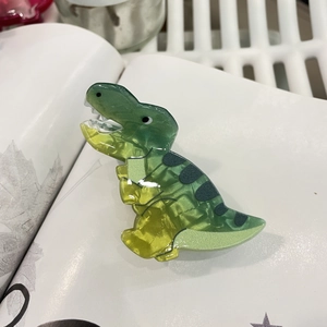 Detail of cute green gradient dinosaur hair claw clip made of glossy acetate material