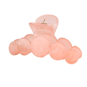 Detail of a peach pink translucent hair claw with bubble-shaped teeth and gold spring
