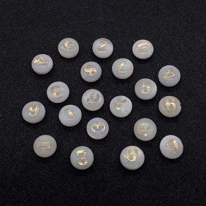 Dettaglio di perle tonde piatte da 8mm in madreperla con numeri dorati per gioielleria