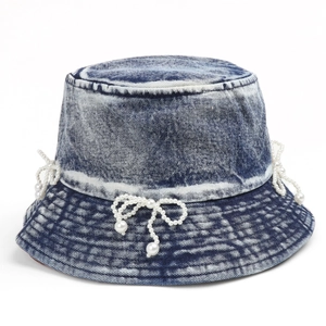 Detail of light blue denim bucket hat with decorative pearl bow embellishments