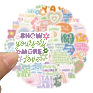 Close-up of hand holding a pink vinyl sticker showing yourself more love quote