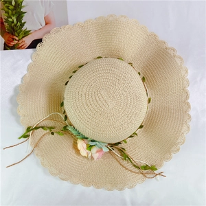 Foldable women's straw sun hat with large wavy brim and elegant floral decoration