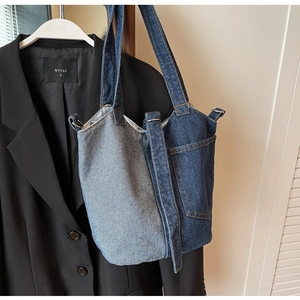 Detail of blue patchwork denim bucket bag texture hanging on a black blazer jacket