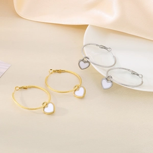 Detail of twisted hoop earrings with heart-shaped pendants in gold and silver finish
