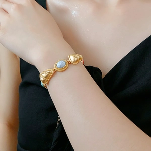 Close-up of vintage gold triangle beaded bracelet with white turquoise stone on wrist