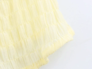 Close-up of pale yellow smocked fabric with detailed ruffled texture and breathable weave