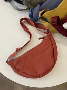 Multiple colors of nylon crescent crossbody bags in a stacked overhead product display