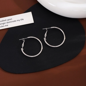 Minimalist silver hoop earrings featuring a classic round design on a brown background