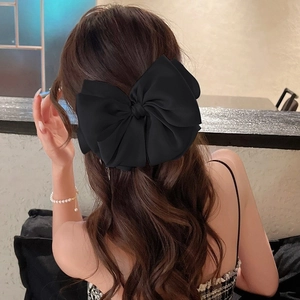 Détail d'une grande pince à cheveux avec nœud en satin noir porté par un mannequin