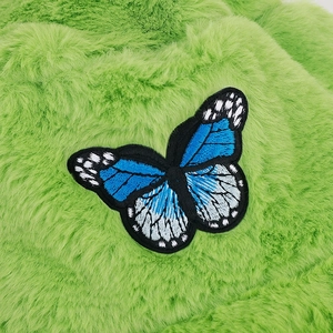 Detail of blue butterfly embroidery on green plush bucket hat with soft faux fur texture