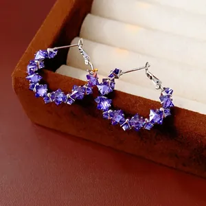 Elegant purple crystal hoop earrings with silver pins on a brown velvet jewelry box