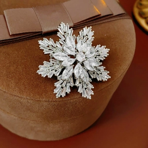 Detailed close-up of a silver snowflake brooch with sparkling zircons on a velvet box