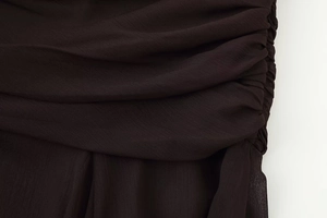 Detailed close-up of dark brown chiffon dress featuring intricate ruched pleated design