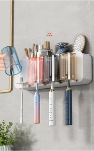 Detail of wall-mounted toothbrush holder with four colorful cups and storage shelf