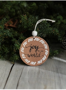 Detail of circular wooden Christmas ornament with Joy To The World print on pine branch
