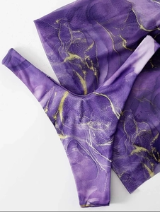 Macro shot of purple marble pattern fabric with gold veins on ribbed swimwear fabric