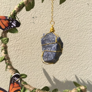 Macro detail of blue crystal moon wind chime with gold wire wrap and butterfly accent