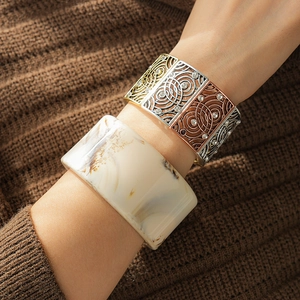 Detail of vintage resin marble bangle and tricolor metal hollow bracelet on wrist