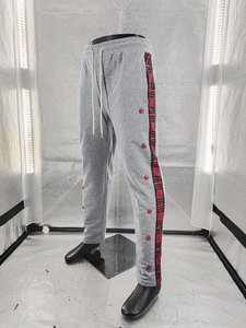 Detail view of men's grey casual pants featuring red plaid side stripes and snap buttons