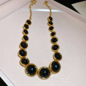 Macro detail of vintage gold necklace with black resin circular pendant in a jewelry box