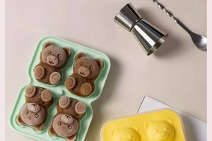 Detail of four brown 3D bear-shaped ice cubes in a light green silicone mold