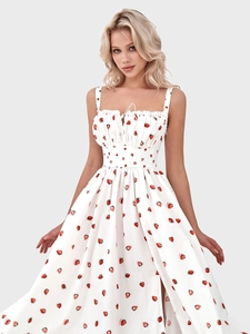 Detailed view of red strawberry prints on a white sundress with a side slit design