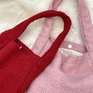 Detail of red and pink bouclé tote bags featuring magnetic closure and soft plush texture
