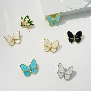 Natural mother-of-pearl butterfly brooches set with pearls and rhinestones on white stands