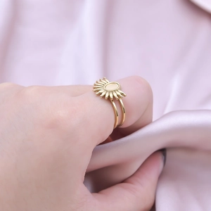 Detailed close-up of golden sunflower shape ring with oval base on silk fabric