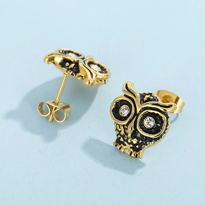 Vue détaillée de boucles d'oreilles hibou dorées avec détails noirs et cristaux