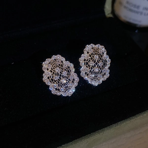 Gros plan de boucles d'oreilles ovales argentées évidées avec zircons sur velours noir