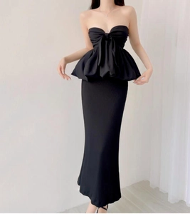 Detail of black strapless dress featuring a large front bow and elegant ruffled hemline
