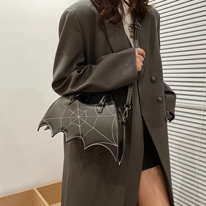 Detail of bat-wing handbag featuring white embroidered spider webs and metal hardware