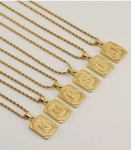 Detail of 18K gold stainless steel alphabet square pendants on twisted rope chains