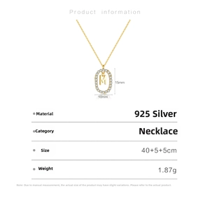 Detail of 925 sterling silver gold necklace with letter M oval pendant and zircon stones