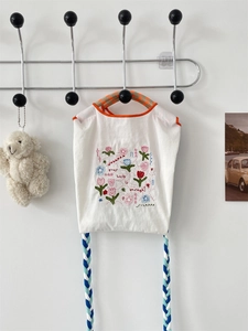 Détail d'une broderie florale sur un mini sac en tissu oxford blanc avec cordes tissées