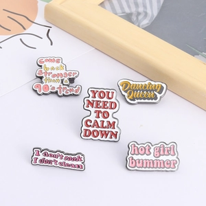 Set of five enamel slogan pins including Dancing Queen on white surface with art card