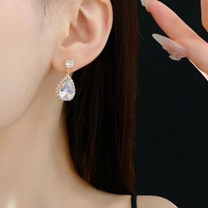 Détail de boucles d'oreilles en forme de goutte en zircon doré portées par un mannequin