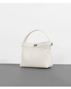 Detail shot of white woven texture and metallic clasp on the top handle Kelly bag