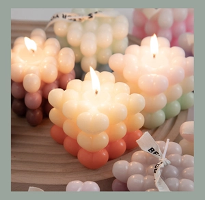 Macro view of gradient cube bubble candles with Best For You ribbon and warm flame