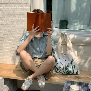 Outdoor shot of a cream canvas tote bag with chamomile print and casual summer outfit