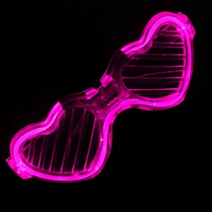 Macro shot of glowing pink heart-shaped shutter LED glasses in a dark setting