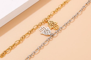 Detailed macro of gold and silver Hamsa hand bracelets with hollow carved palm charms