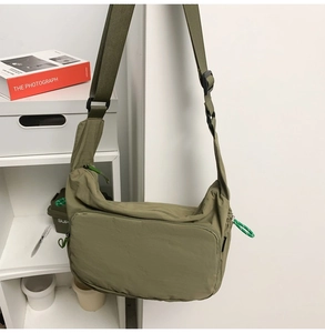 Detail of adjustable wide shoulder strap and woven zipper puller on nylon messenger bag
