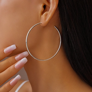 Close-up of large minimalist silver C-shaped hoop earrings on female model